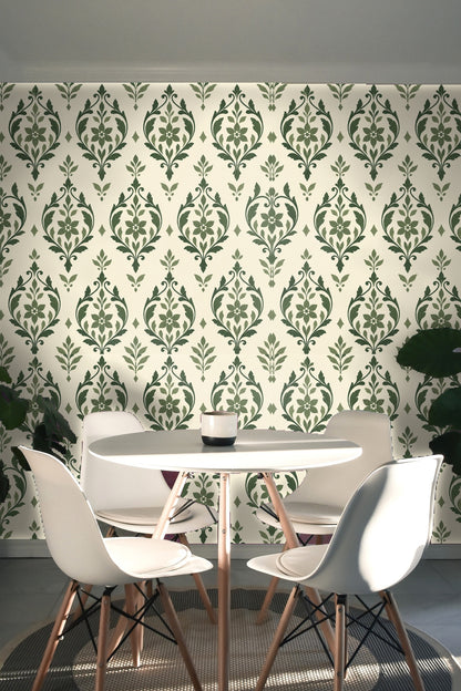 Angled view of sage arabesque wallpaper beside baseboard and hardwood floor