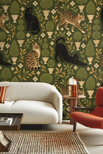Living room with olive green wallpaper featuring black and tabby cats and topiary trees behind light wood table