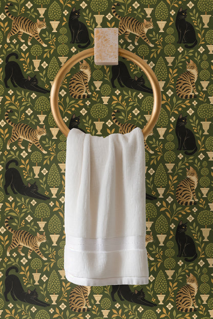 Tabby cat looking back amid botanical wallpaper in olive hues