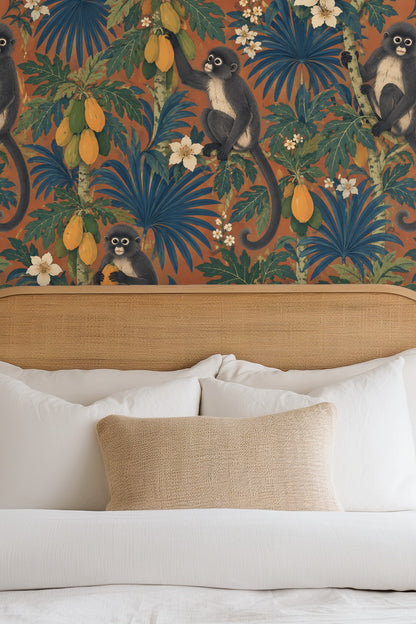 Close-up of wallpaper featuring hand-painted monkeys clutching papayas on terracotta background with lush foliage
