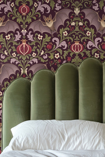 Close-up of leather armchair against wallpaper with flying bats and intricate pomegranate foliage pattern.