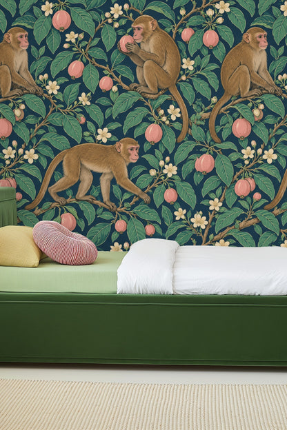Living room with Guava Macaque Garden wallpaper in deep teal with macaque motif behind white curved sofa and orange chair.