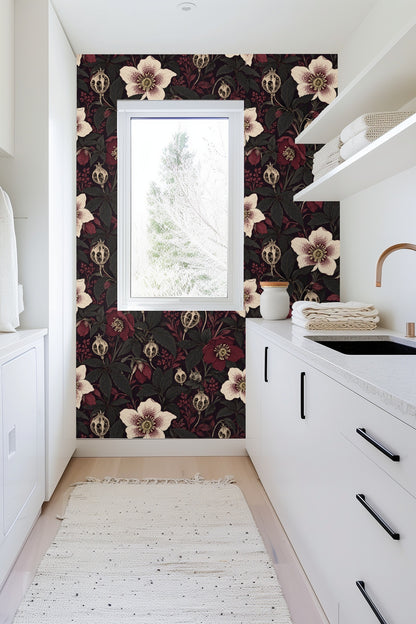 Detail shot of a white hellebore flower with burgundy speckles and dark leaves on wallpaper