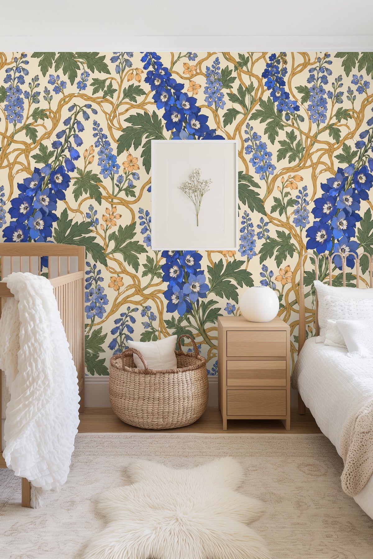 Living area with cream sofa and round wooden table in front of wallpaper featuring blue delphiniums and twisting golden vines