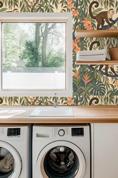 Soft candle and delicate white flowers in clear glass vases against wallpaper with playful monkeys and lush foliage