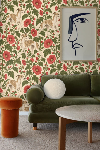 Green velvet sofa with white round pillow and framed minimalist artwork against wallpaper of greyhounds and red hollyhocks
