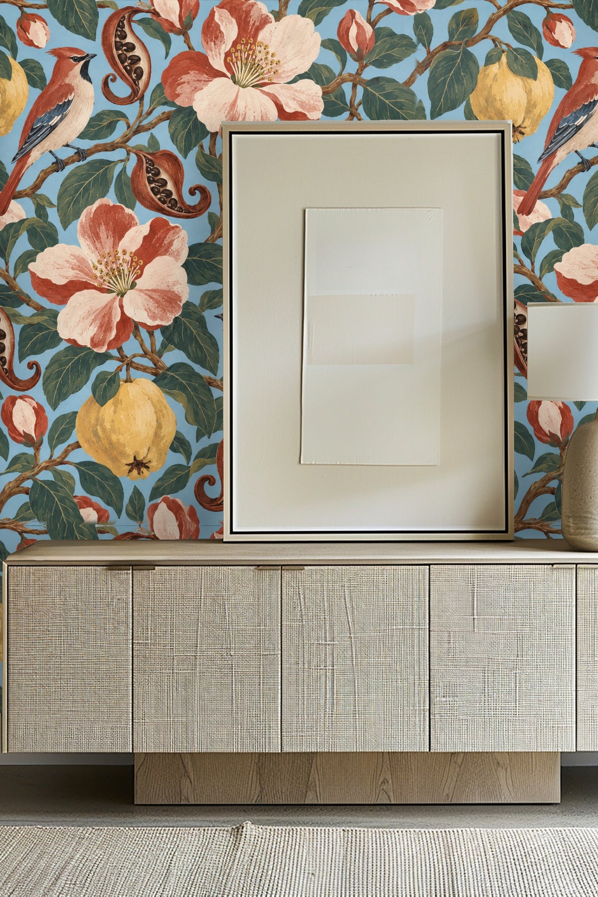 Close-up of wallpaper featuring quinces, waxwing birds, pomegranate seeds and large terracotta-pink flowers on a sky blue background
