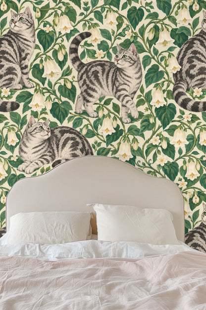 Living room wall with Bellvine Cat Tangle wallpaper, showing tabby cats amidst lush green foliage and white bell flowers.