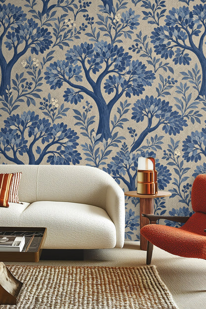 Living room with cream sofa and wooden table against wallpaper with blue leafy trees and herringbone texture