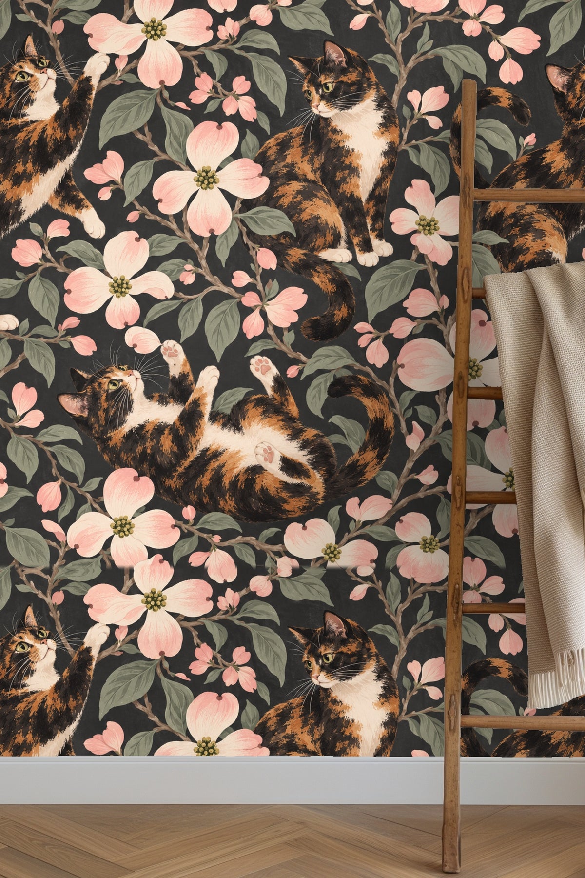 Wallpaper pattern showing calico cats with blush dogwood flowers on a charcoal background.