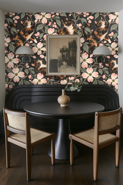 Branch of dogwood flowers with light pink blossoms and green leaves on wallpaper.