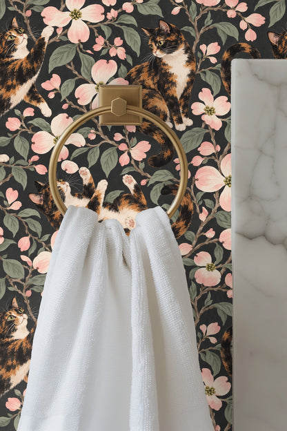 Close-up of a calico cat lounging amid dogwood flowers on wallpaper.