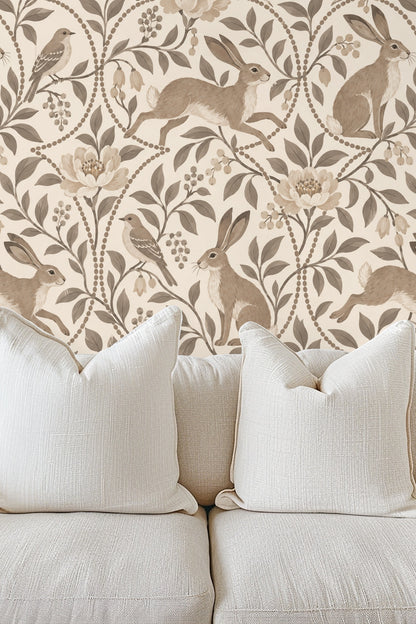 Bedroom wall covered with Pebble Hare & Songbird wallpaper behind a bed with white pillows and beige throw