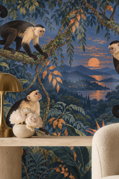 Distant layered mountains lit by a warm orange sunset behind tropical leaves and monkeys.