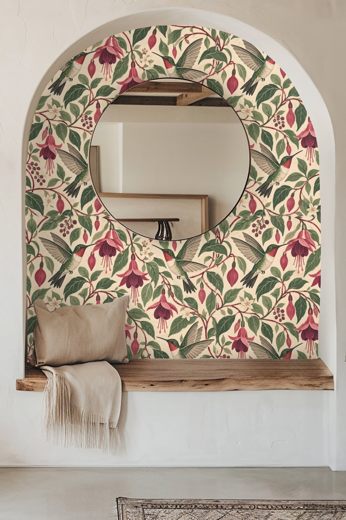 Entryway wall with Nectarwing Fuchsia wallpaper framing a round mirror over a wooden bench with beige throw.