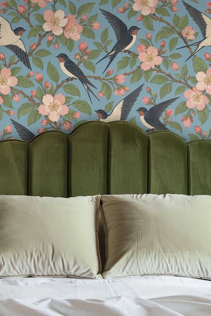 Wallpaper pattern showing swallows in flight and perched on blossoming branches with green leaves on blue background