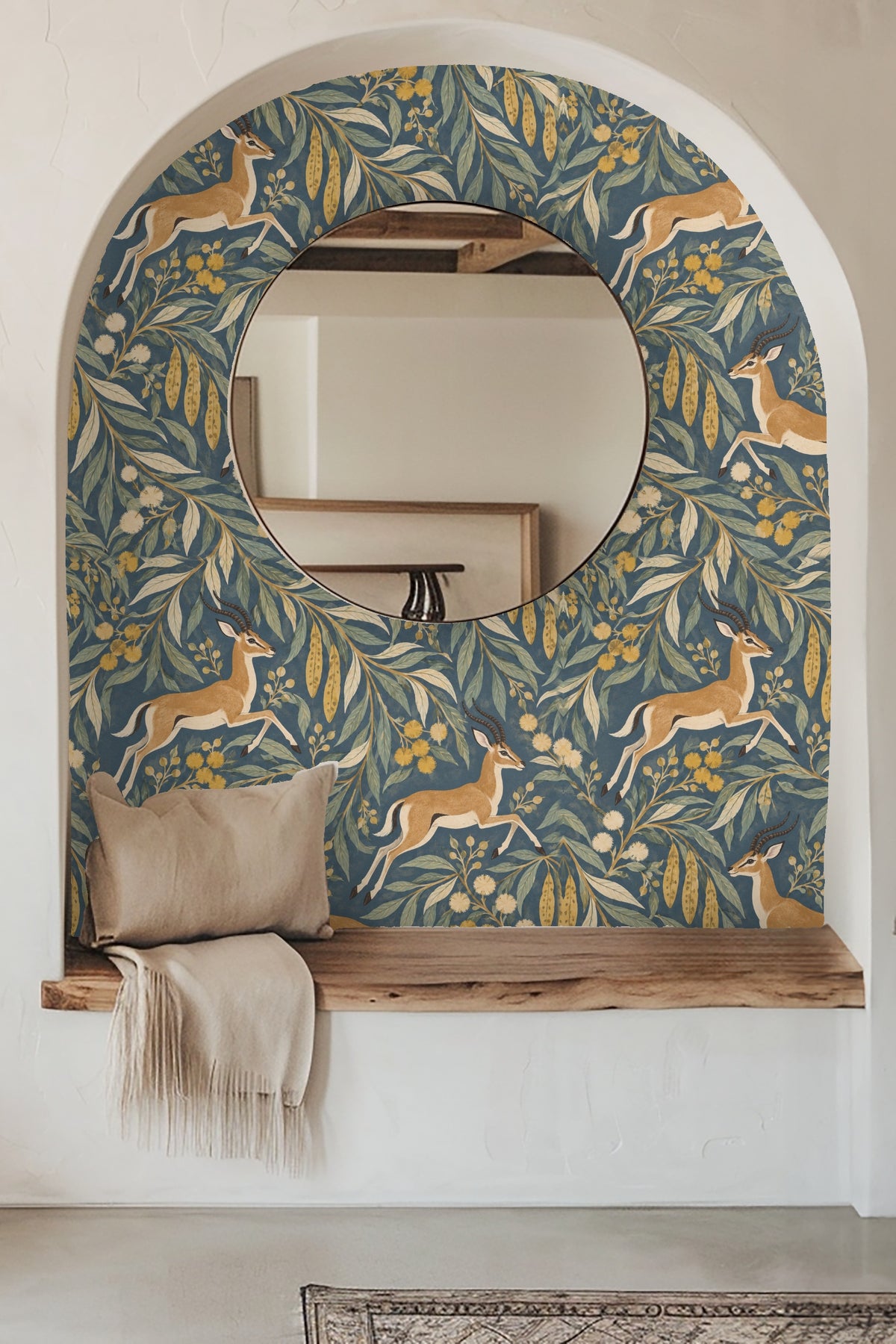 Blue velvet sofa in front of the Impala Leaf Procession wallpaper with ochre and green leaf motifs