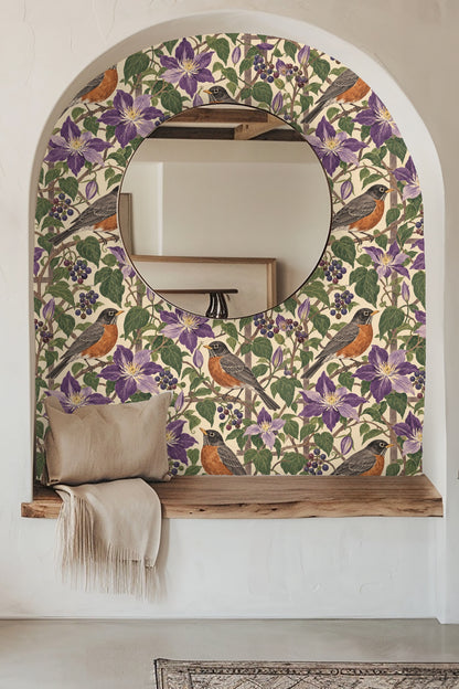Close-up view of wallpaper with violet clematis flowers, robins, and berry clusters accented by a lit candle and flowers
