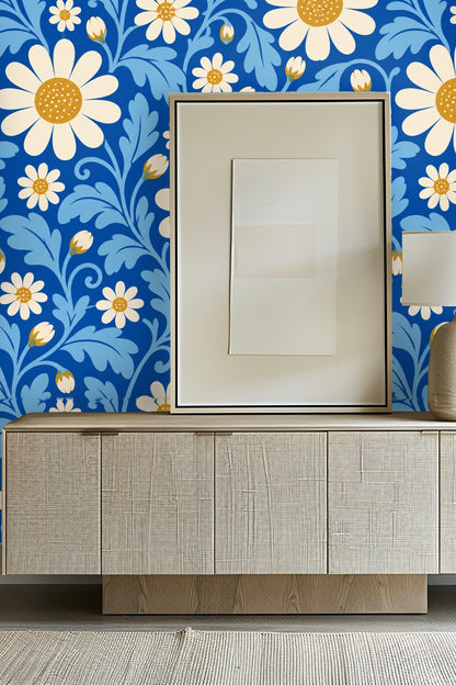 Close-up of plush blue velvet couch in front of wallpaper with large white daisies and blue foliage