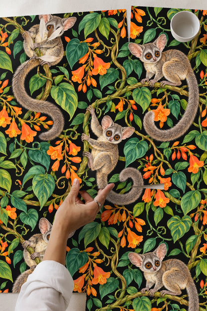 Close-up of two galagos clinging to intertwined vines with vivid orange trumpet flowers on black ground.