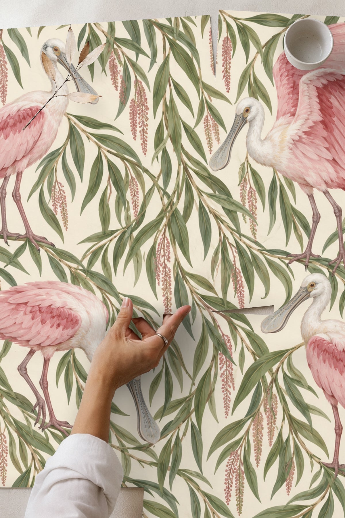 Living room wall with pink spoonbill and willow wallpaper behind a sofa with earthy cushions