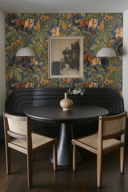 Blue velvet sofa cushion with wallpaper of monkey and chestnut branches behind.