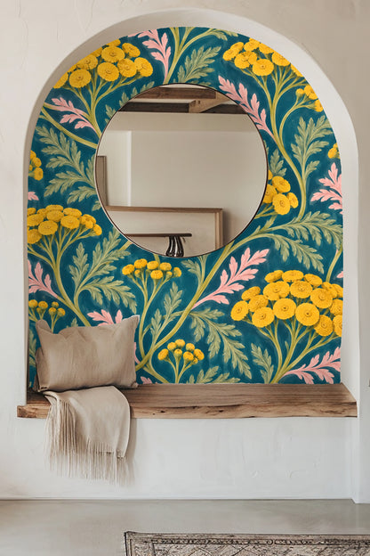 Detail of a candle and dried flowers positioned in front of a wallpaper with yellow tansy blooms and pink leaves on teal