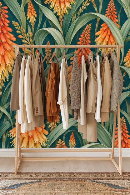 Curved green leaves arching around clusters of orange torch flowers on the wallpaper