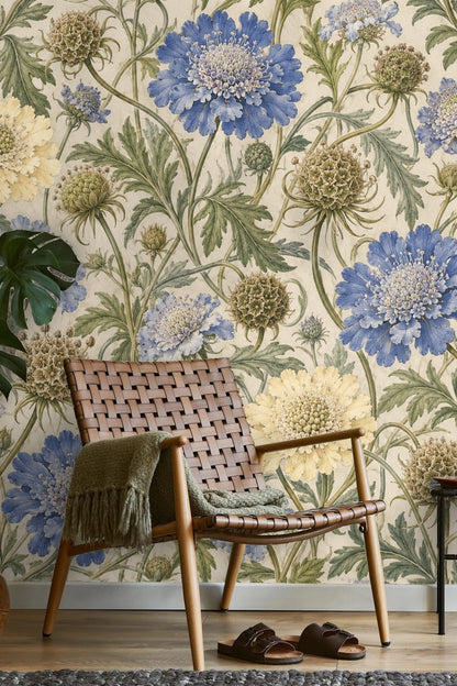 Living room setting with botanical wallpaper behind a grey sofa, pillows and small table