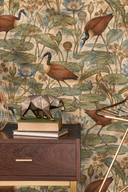 Room view with Jacana Lily Step wallpaper behind a beige armchair and wooden cabinet