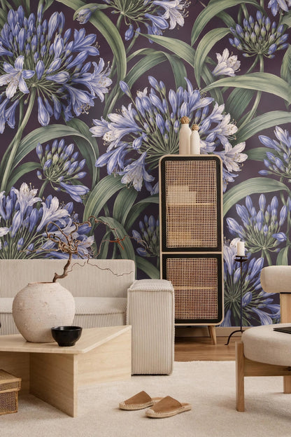 Playroom with child's white playhouse and table set against a wall covered by Agapanthus Rainwheel wallpaper featuring blue agapanthus bloom