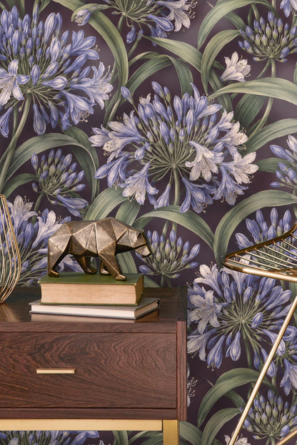 Partial view of a wall with Agapanthus Rainwheel wallpaper behind a wooden chair.