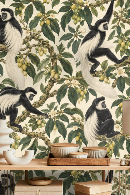 Side view of colobus monkey reaching for fruit amidst detailed botanical leaves on wallpaper.