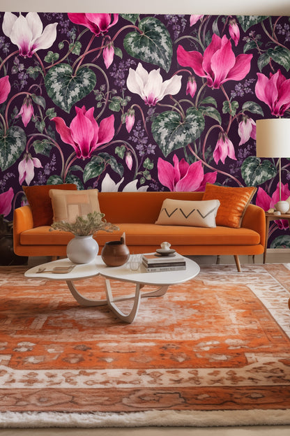 Living room featuring cyclamen wallpaper behind woven leather chair with green throw