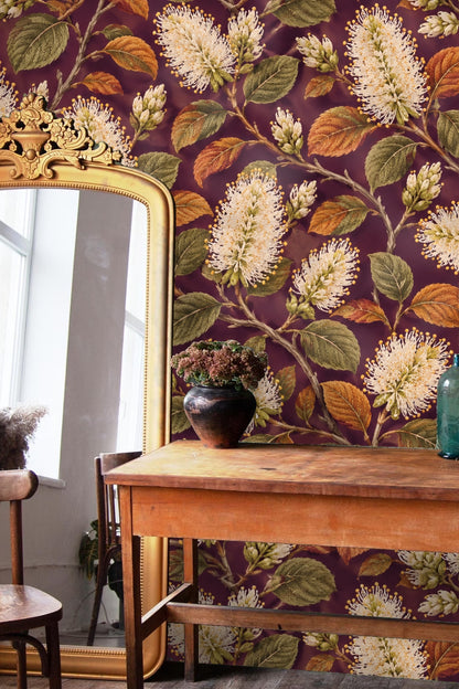 Branch details with cream bottlebrush flowers and leaves in olive and burnt orange hues on plum