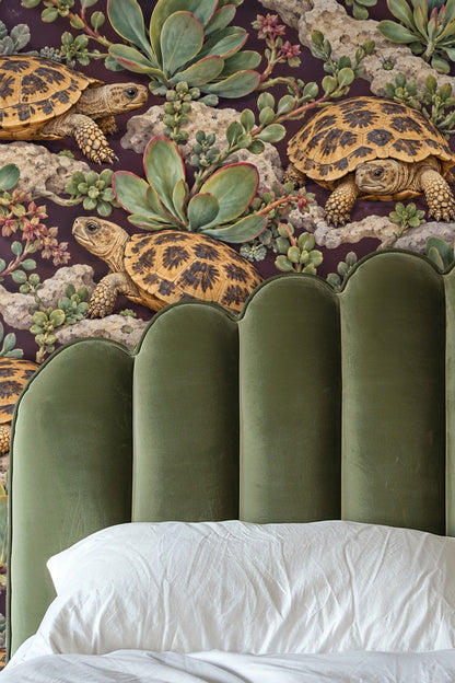 Detailed wallpaper pattern featuring pancake tortoises among succulents and rocky outcrops on plum background.