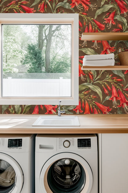 Interior detail showing scarlet trumpet floral wallpaper behind a white candle and delicate white flowers in a glass vase