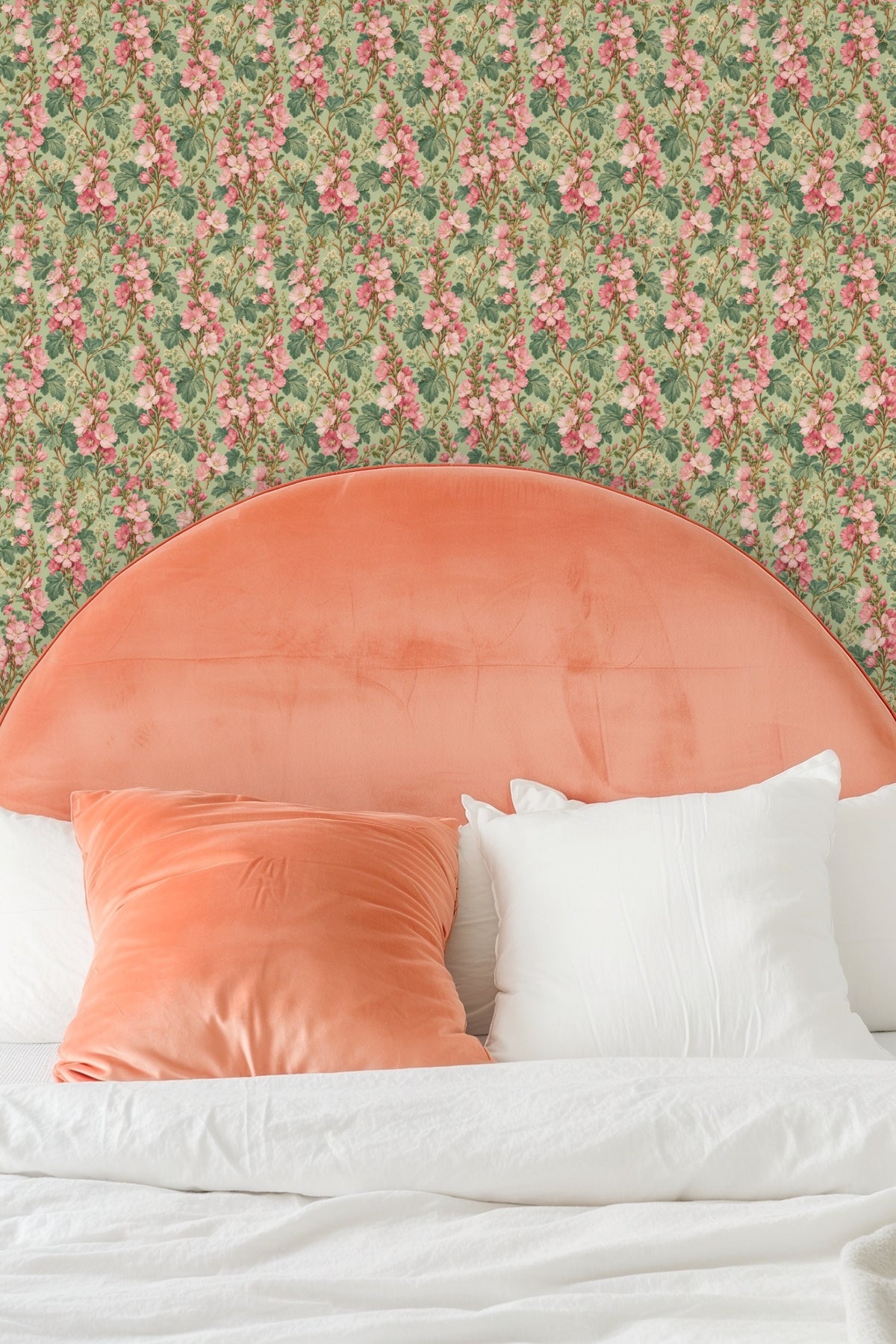 Wallpaper pattern with pink floral columns displayed behind cream pillows on a beige couch
