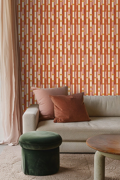 Soft pink pillows complementing warm terracotta and cream wallpaper behind a bed.