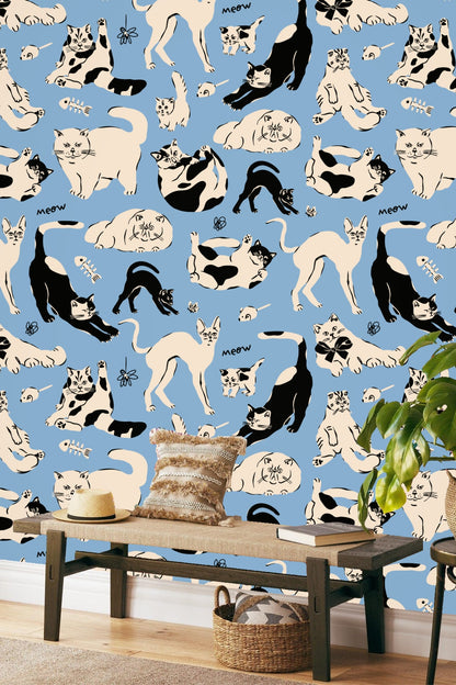 Living room wall adorned with blue wallpaper patterned with black and cream cats, mauve sofa in foreground