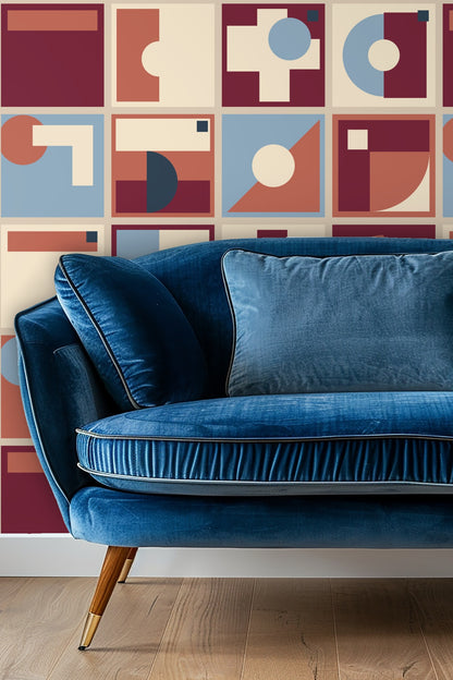 Blue velvet couch set against geometric wallpaper in dusty rose, navy, cream, and burgundy creating a refined modern space.