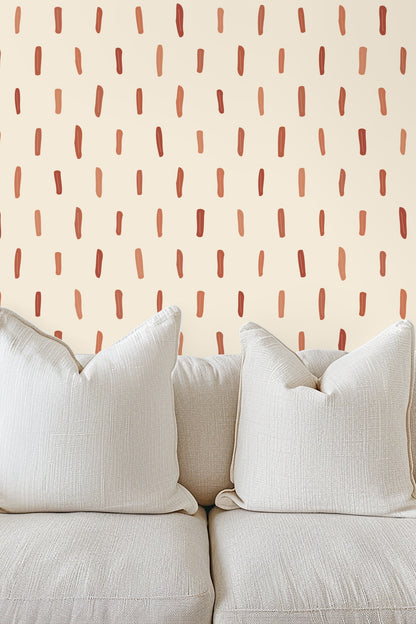Nursery room featuring wallpaper with vertical terracotta brushstrokes behind a light wooden crib.
