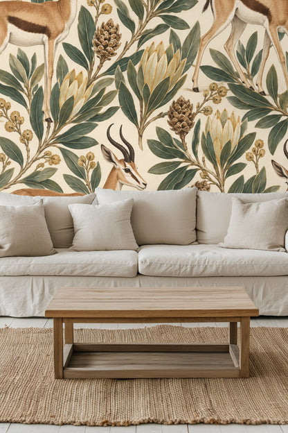 Bedroom wall covered in springbok and protea wallpaper behind a green velvet headboard with cream pillows.