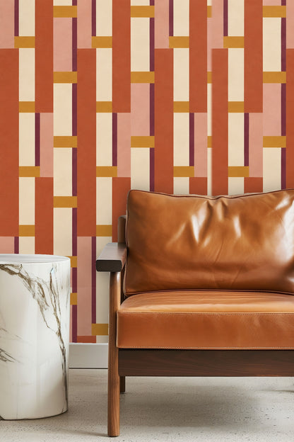 Living room with terracotta and dusty rose geometric wallpaper behind an orange velvet sofa and patterned rug
