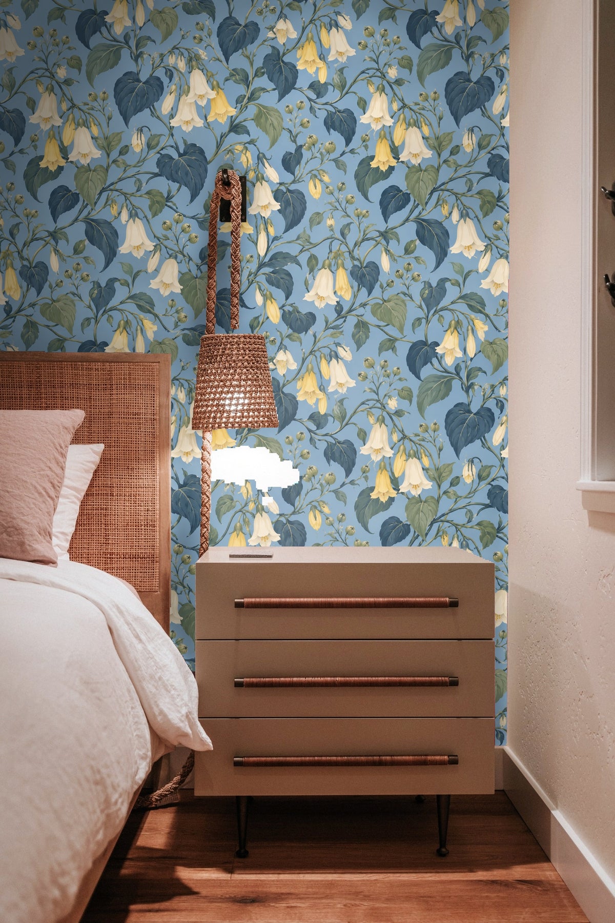 Artistic workspace with hand holding paper and showing floral wallpaper sample