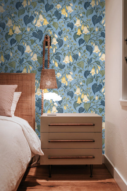 Artistic workspace with hand holding paper and showing floral wallpaper sample