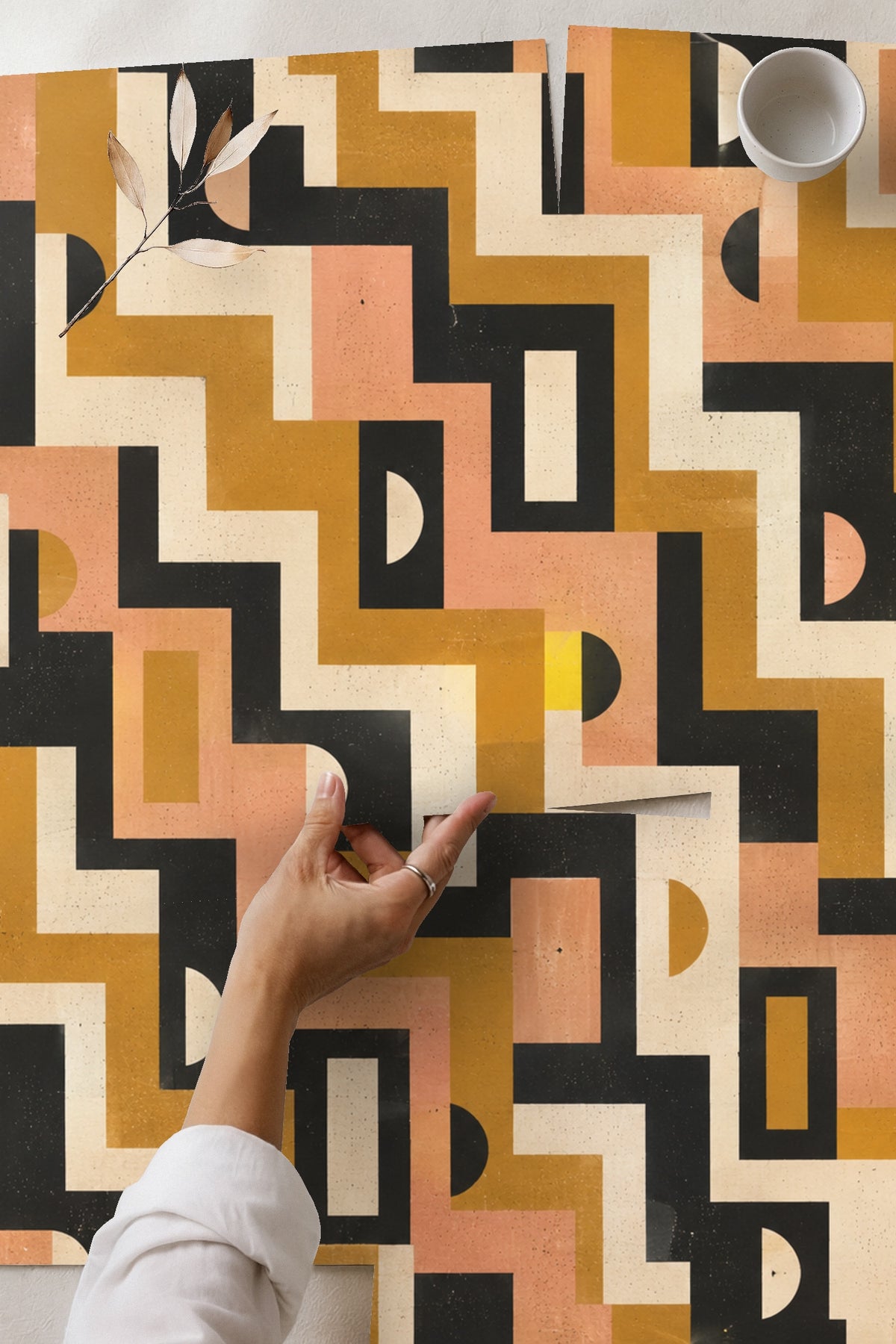 Lifestyle image of Mid-Century Mod Geometry wallpaper behind green mid-century style chair with wood armrests and striped pillow