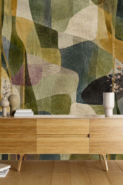 Focused view of velvet green pillows in front of abstract wallpaper.