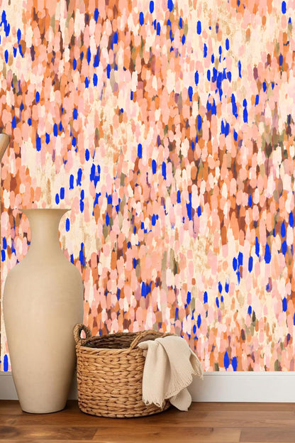 Living room scene with blue chair and sculptural vases against coral and cobalt impressionist wallpaper
