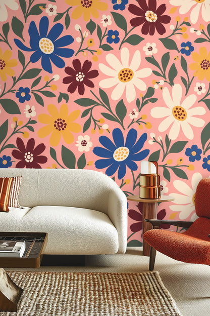Wallpaper close-up showing large daisies in white, blue, and mustard yellow with green leaves on a pink background